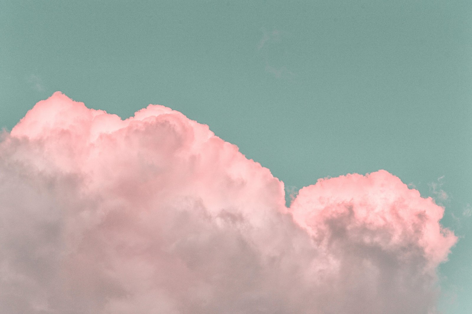 Pastel pink clouds in a clear blue sky create a serene and dreamy atmosphere.