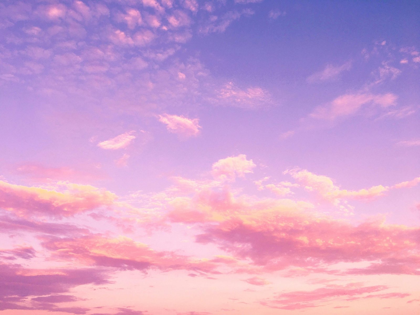 A dreamy pink and purple cloud-filled sky at sunset, creating a serene and tranquil atmosphere.
